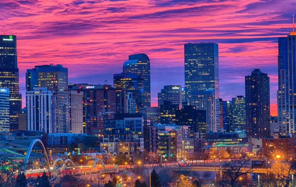 A pink and blue sky behind Denver skyline at dusk